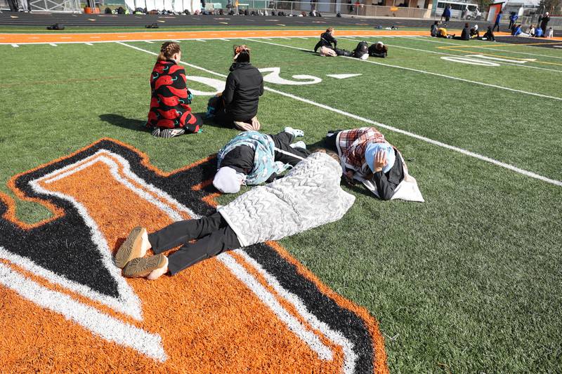 Minooka runners huddle up in blankets before the start of the Minooka track invitational. Thursday, April 14, 2022, in Minooka.
