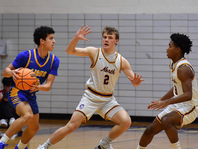 Lyons Township’s Dylan Holcer (left) looks to pass as Downers Grove North’s Jack Romsey  and Kam Ganier  defend during a game on January 15, 2026 at Downers Grove North High School in Downers Grove .