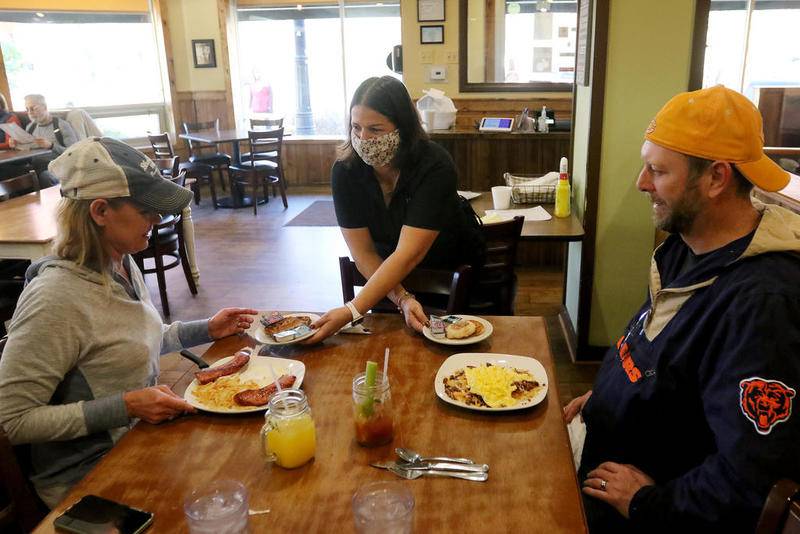 Double Yolk Cafe server Lorie Polanco (center) delivers food to indoor dining customers Christina and Ryan Allison of Woodstock on Saturday in Woodstock.