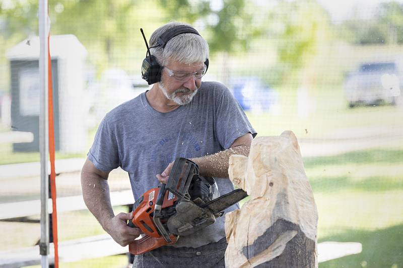 Dave Ferrell carves into a stump of wood Wednesday, July 31, 2024 at the Ogle County Fair. The wood sculptures will be auctioned off on Saturday with the proceeds going to fund the fair.
