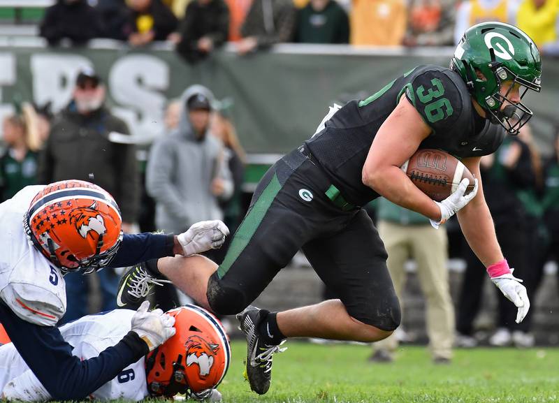 Glenbard West's Jack Moellering (36) lunges away from two Naperville North tacklers during an IHSA Class 8A playoff game on Oct. 28, 2023 at Glenbard West High School in Glen Ellyn.