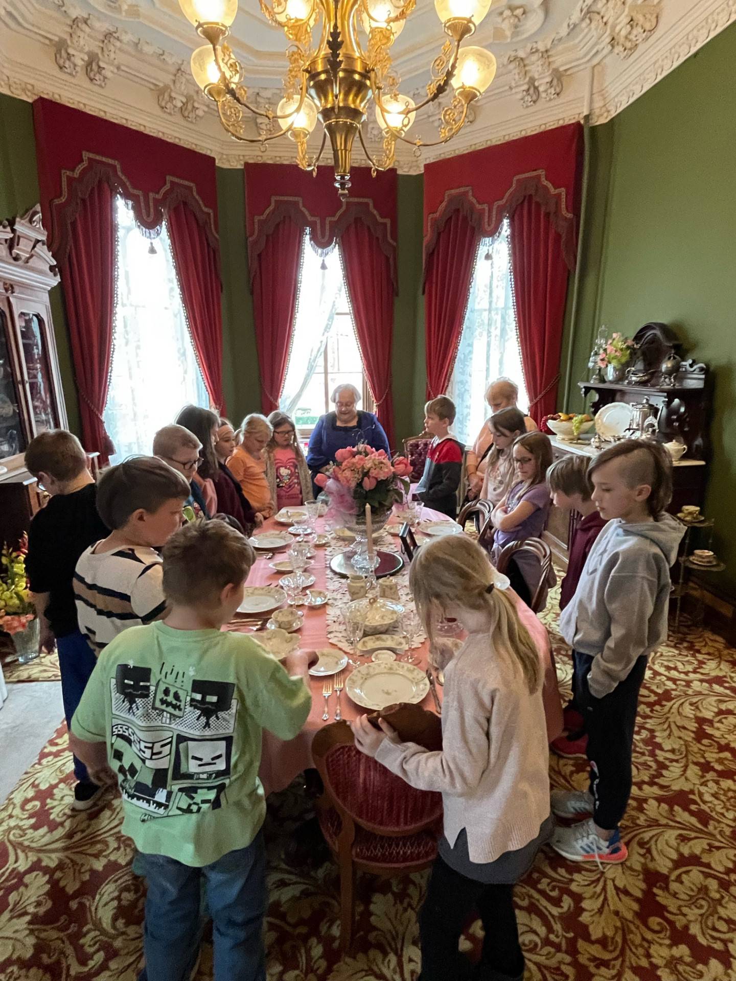 RMA president Lorraine McCallister gathers Grand Ridge students around the dining room table to discuss how a meal would have been served in Victorian times.