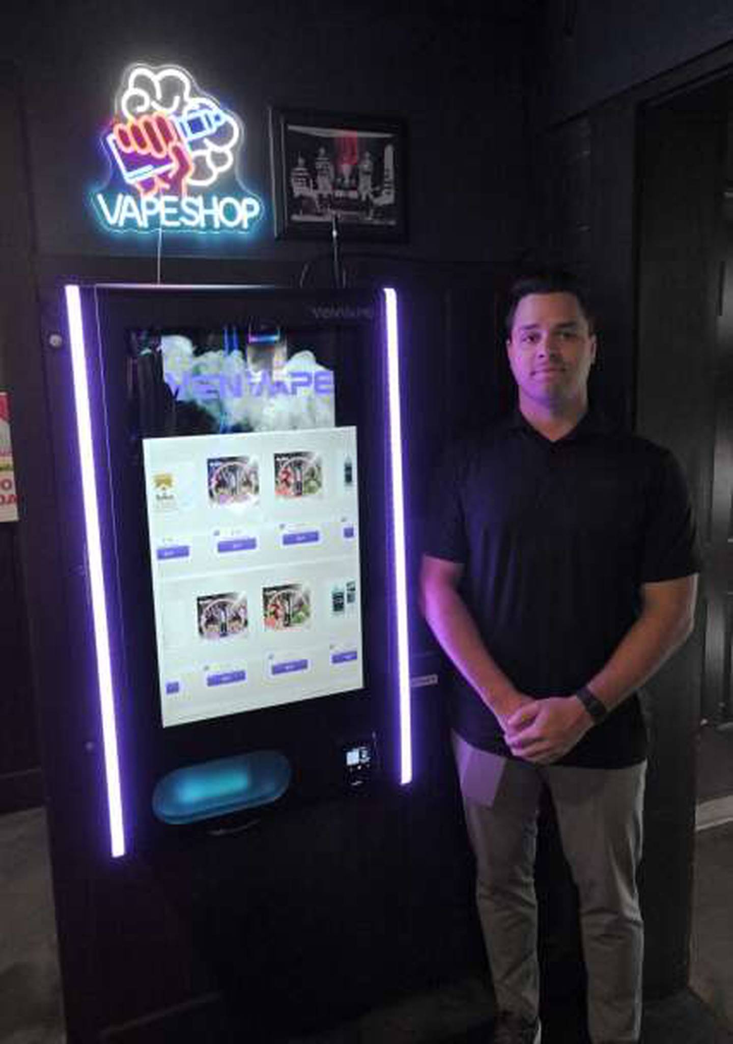 John Floro, co-owner of Elmhurst-based VenVape, poses with one of his vape vending machines at Local Bar & Grille in Wood Dale. The machine scans driver’s licenses before allowing a credit card purchase.