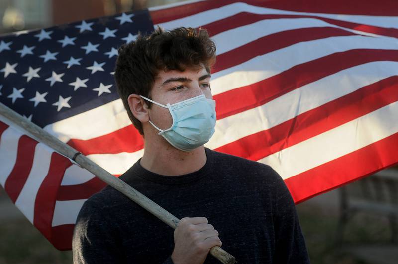 MoAlex Wojnicki, 18, of Woostock, holds an America Flag as people gather Saturday afternoon, Nov. 07, 2020, in the historic Woodstock Square to celebrate President-elect Joe Biden and Vice President-elect Kamala D. Harris being declared the projected winners of the election.