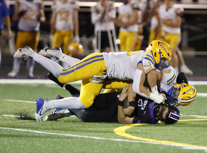 Downers Grove North's Owen Kansu (1) is smothered by the Lyons' Pat Cheney (8) and Ayman Soltan (78) during the varsity football game between Downers Grove North and Lyons Township on Friday, Oct. 11, 2024 in Downers Grove.