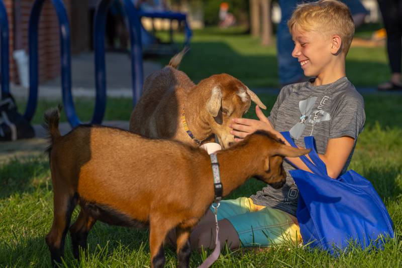 James Rexroat plays with goats at the petting zoo during the National Night Out event Tuesday, Aug. 5, 2025, in Seneca.