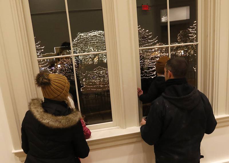 A family looks out of the old courthouse windows after the Lighting of the Square Friday, Nov. 29, 2024, in Woodstock. The annual holiday season event featured brass music, caroling, free doughnuts and cider, food trucks, festive selfie stations and shopping.