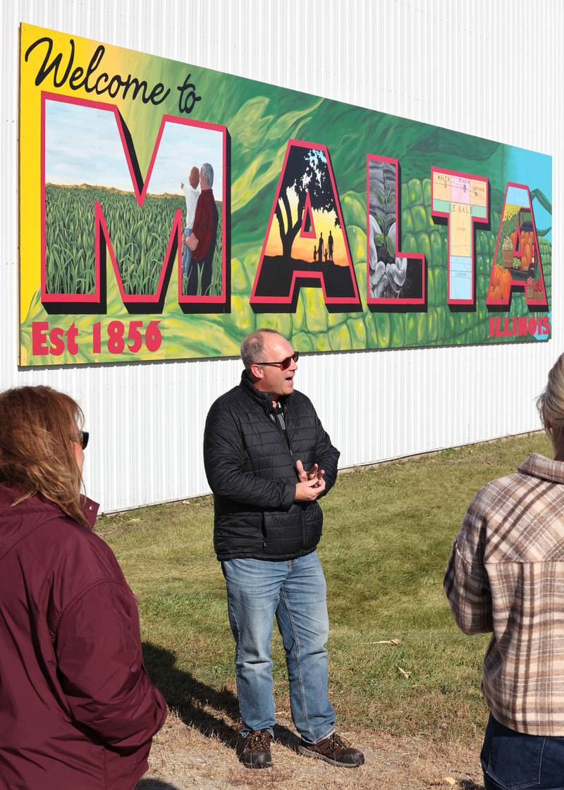Malta Village President Bob Iverson talks about the new mural by Dixon artist Nora Balayti before the official ribbon cutting Wednesday, Oct. 19, 2022, on the north side of Route 38 in Malta. The mural, which spells out Malta in large capital letters, depicts the values of the town with themes of agriculture, family, community and growth.
