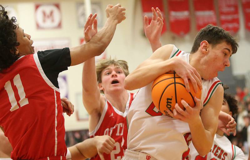 L-P's Nick Olivero pulls in a rebound over Ottawa's Hezekiah Joachim and Owen Sanders on Friday, Feb. 7, 2025 in Sellett Gymnasium at L-P High School.