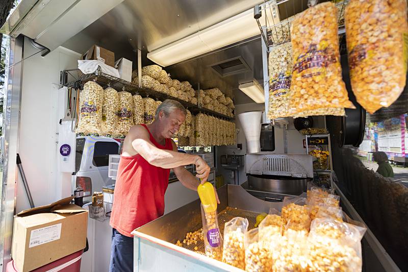 Mark Thomsen fills popcorn bags at his and his wife Lisa’s stand Saturday, Aug. 10, 2024 at the Carroll County Fair.