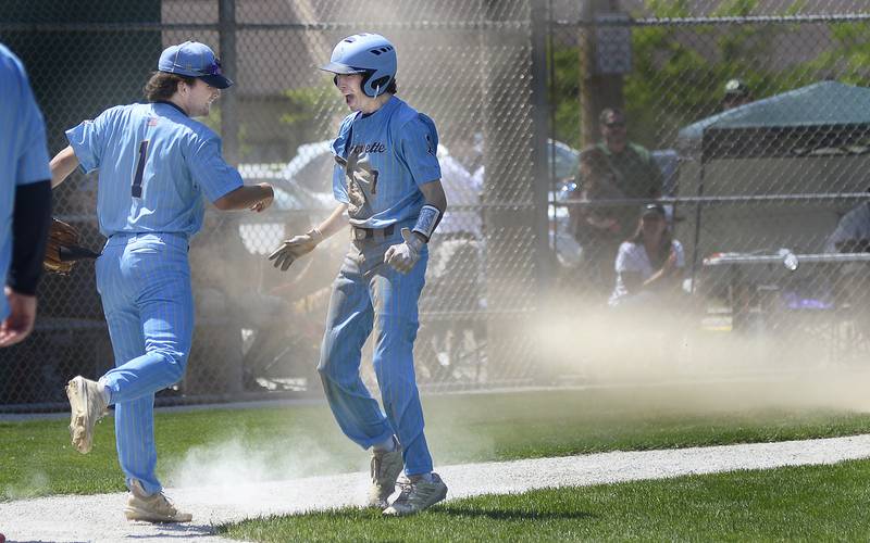 Marquette’s Tommy Durdan greets a jubilant Gabe Almeda who leaving a cloud of dust scored Marquette’s third run during on Saturday, May 20, 2023 at Masinelli Field in Ottawa.