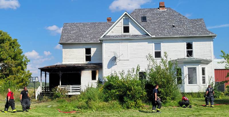 Firefighters from the Utica Fire Department secure the area around a fire-damaged house along Dee Bennett Roach in Utica on Monday.