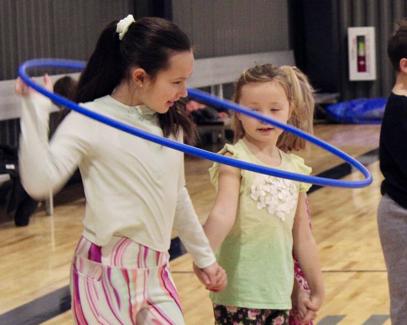 Eliana Mortimer tries to pass through a Hulu Hoop without breaking the human chain as part of a cooperative relay game on Tuesday during the Winter Mini Spark day camp at The Facility in Dixon.