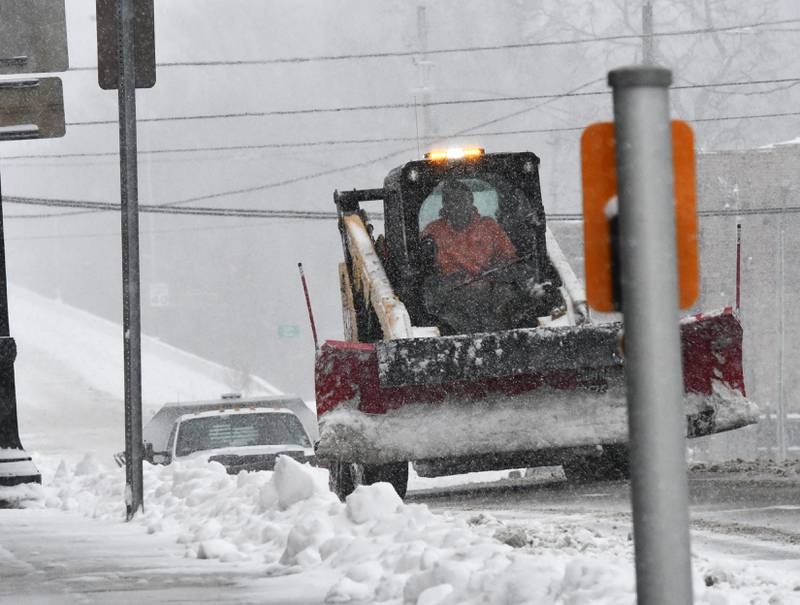 An employee of Oregon's Public Works department clears snow from sidewalks in the city's downtown on Saturday  afternoon, Nov. 29, 2025. The Oregon Chamber of Commerce's Candlelight Walk was rescheduled to Dec. 6 due to the snow storm.