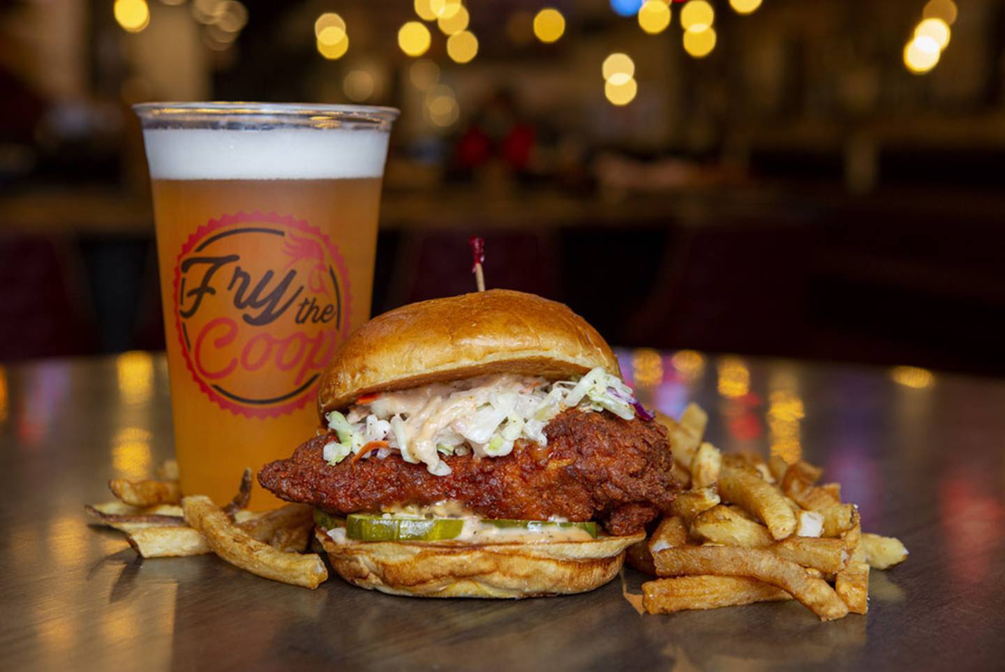 Fry the Coop hot chicken sandwich with fries and a beer. Fry the Coop will open its tenth location in Joliet on Aug. 14, 2025.