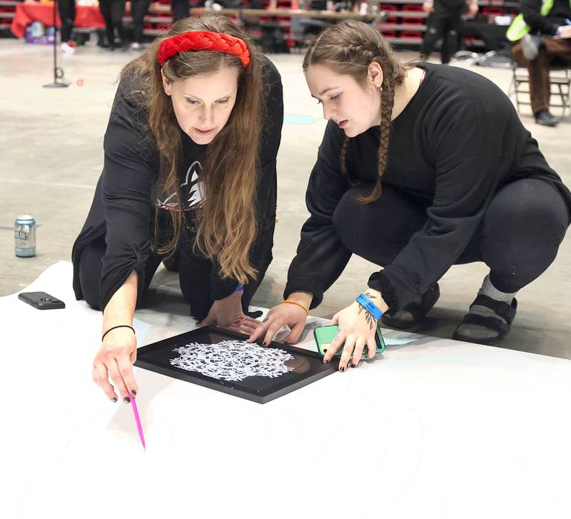 Jessica Labatte, Northern Illinois University associate professor of art, (left) and  photography student Emma Vitally, a senior, draw out a design on the giant paper snowflake they are making along with other students in the photography department Tuesday, March 29, 2022, in the Convocation Center at NIU in DeKalb. The students are attempting to break the world record for the largest paper snowflake.