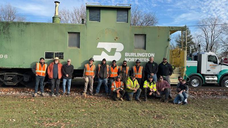 The team from Senica Interstate Towing, MJ Trackworks Inc. and the Streatorland Historical Society pose for a photo Wednesday, Dec. 20, 2023, in front of the new caboose display in Wenona.