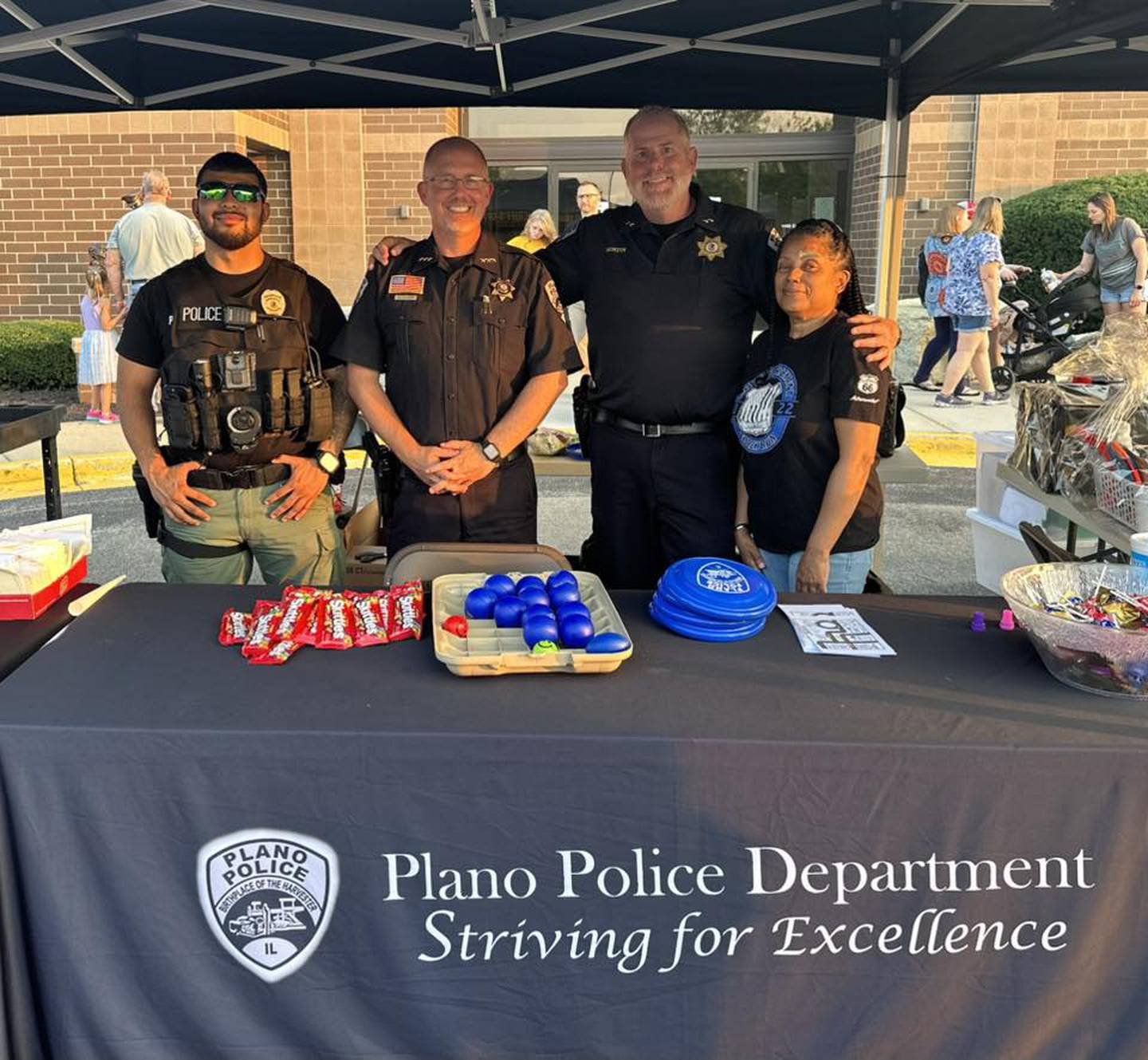 Plano Police Officer Vince Ochoa, Plano Police Chief Norman Allison, Plano Police Deputy Chief Gene Morton and Plano Police Department records clerk Yvonne Hill greet members of the community at the National Night Out event in Yorkville.