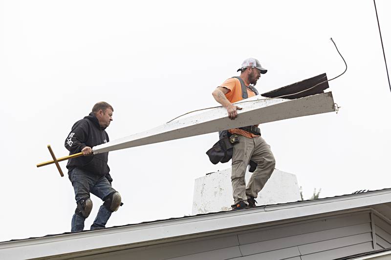 Keith Persico (left) and Adam Benford of Boss Roofing move the steeple from the roof Wednesday, Sept. 13, 2023.