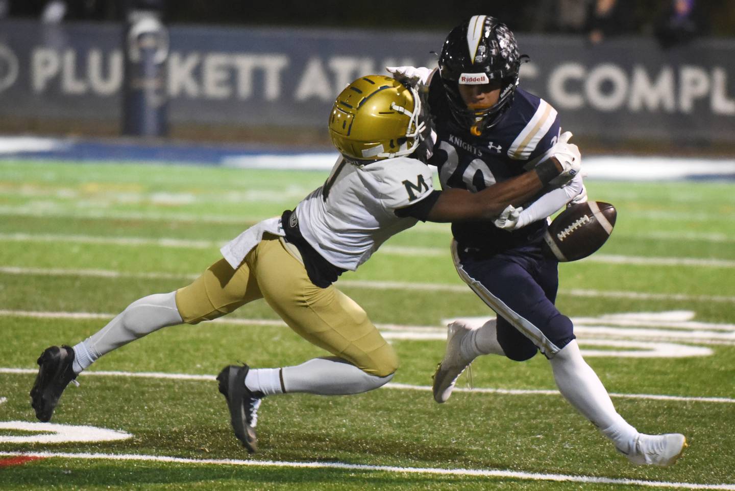 IC Catholic's KC Kekstadt, right, has the ball poked loose by Bishop McNamara's Malachi Lee during an IHSA Class 3A second round playoff game at IC Catholic Friday, Nov. 7, 2025.