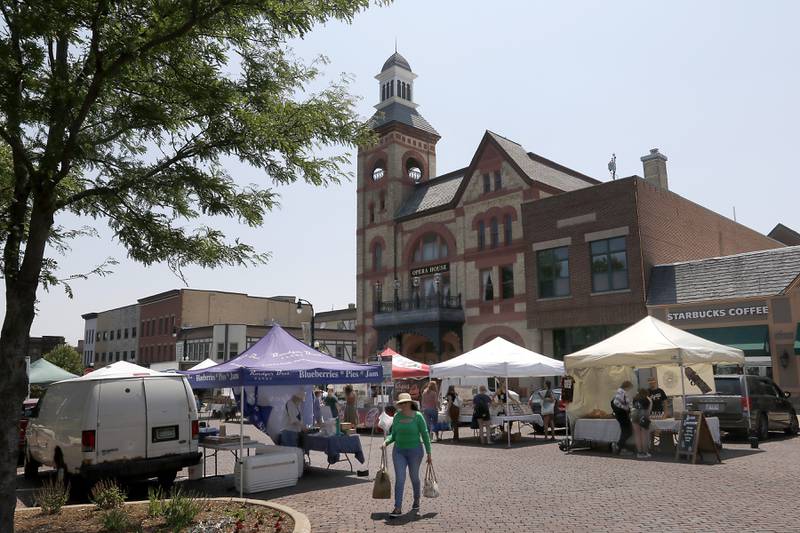 People shops with the Woodstock Opera House in the background on Tuesday, June 20, 2023, during a Summer Woodstock Farmers Market around the Historic Woodstock Square. People were able to shop from over 40 of their favorite farms & producers for in-season food fresh produce, dairy, meats, breads, baked goods, spices, herbs, pasta, flowers and more.