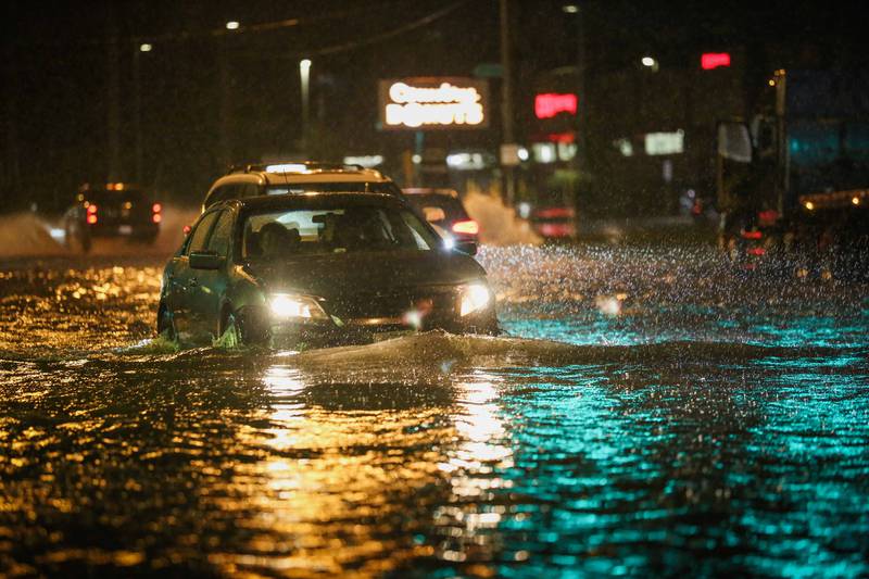 Cars drive on a flooded Route 14 in Crystal Lake during Friday night storms.