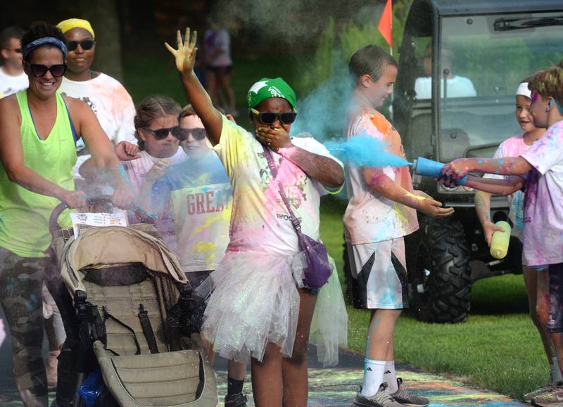 Avah Redmond, 9, of Rockford, covers her mouth as she walks through a cloud of powder during the Oregon Park District's Color Run on Tuesday, July 22, 2025.