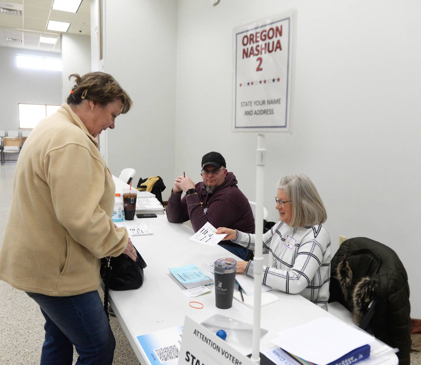 Stephanie Nelson shows her identification to election judges Billy Hardy and Pam Steele at Oregon-Nashua 2 on Tuesday, March 19, 2024 at the Rock River Center in Oregon.
