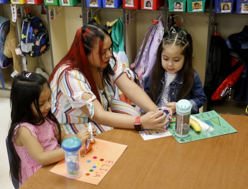 Yasmin Villamar helps a student open her milk Thursday, April 20, 2023, at the deLacey Family Education Center in Carpentersville.