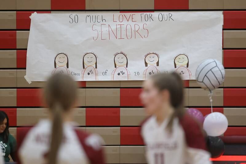 Caricatures of the Plainfield North varsity seniors hangs in the background as the team warms up before the game against Plainfield East on Thursday night.