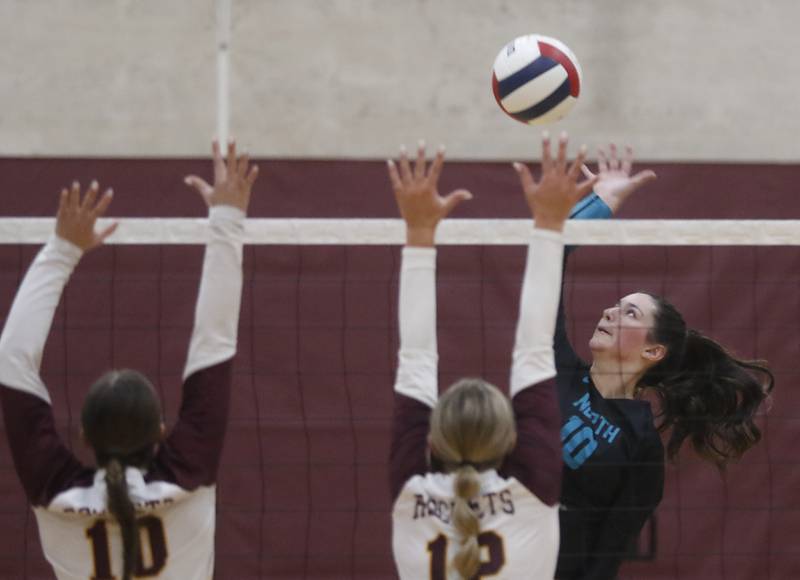 Woodstock North's Ava Kardaras (right) hits the ball over Richmond-Burton's Daniella Mazzola (left) and Richmond-Burton's Zoe Freund (center) during a Kishwaukee River Conference volleyball match on Wednesday, Oct. 15, 2025, at the Richmond-Burton High School in Richmond.