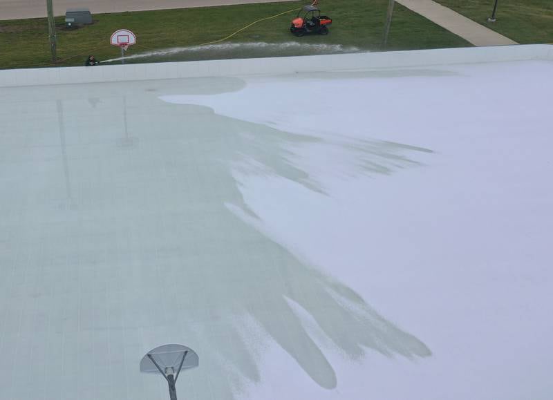 Jim Duncan (top left) sprays water on top of The Schweickert Arena ice rink on Tuesday, Nov. 25, 2025 at Washington Park in Peru. The rink opens this weekend. With the new chiler system, the ice rink is expected to stay open until the end of February 2026.