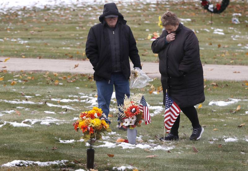 Dennis and Melodee Justen visit the gravesite of their son, U.S. Navy veteran Brian Daniel Justen, during the Veterans Day American Flag Placement at Gravesites of Veterans ceremony on Tuesday, Nov. 11, 2025, in the McHenry County Memorial Park Cemetery, in Woodstock. Members of the Knights of Columbus Patriotic 4th Degree from the Bishop Boylan Assembly placed American Flags at nearly 140 veterans gravesites in the cemetery during the event.