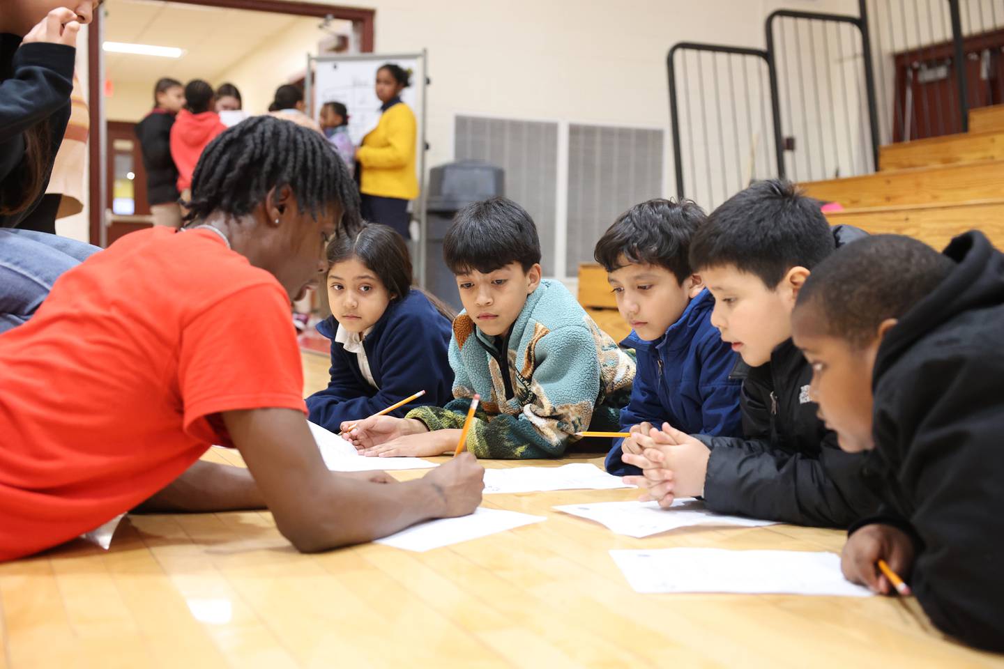 St. Anne High School basketball player Davion Wynne helps grade school students complete their worksheets during the district's Math Madness held on March 20 at the high school.