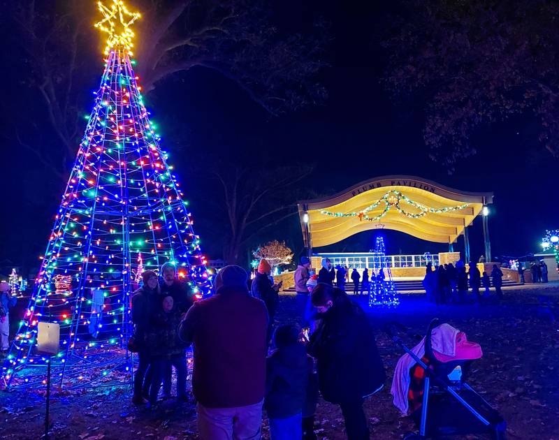 Families gathered around the large lighted Christmas tree Saturday, Nov. 25, 2023, in front Plum Pavilion in City Park during Light Up Streator's park lighting.
