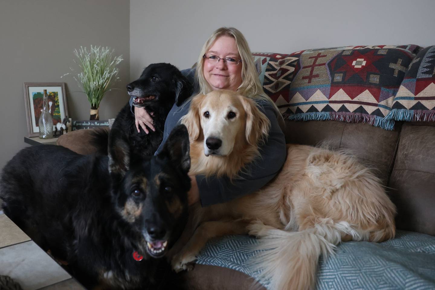 Kathy Vanoskey sits with Teddy, right, Sadie and Dash on the couch in her Minooka home. Vanoskey is raising money to pay for Teddy's surgery, a repair of the canine version of a torn ACL.