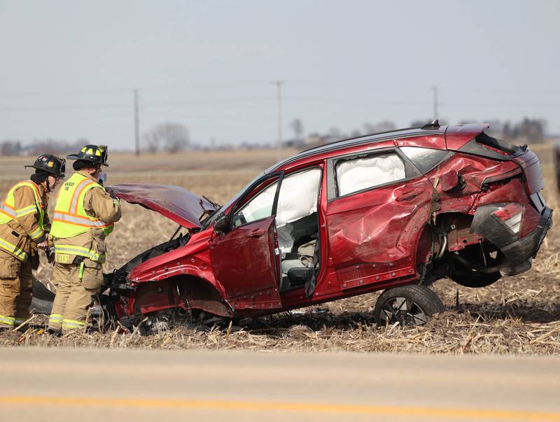 Hinckley firefighters work on a badly damaged vehicle in a cornfield on the east side of Somonauk Road south of McGirr Road Wednesday, March 25, 2026, after a two vehicle crash near Hinckley.