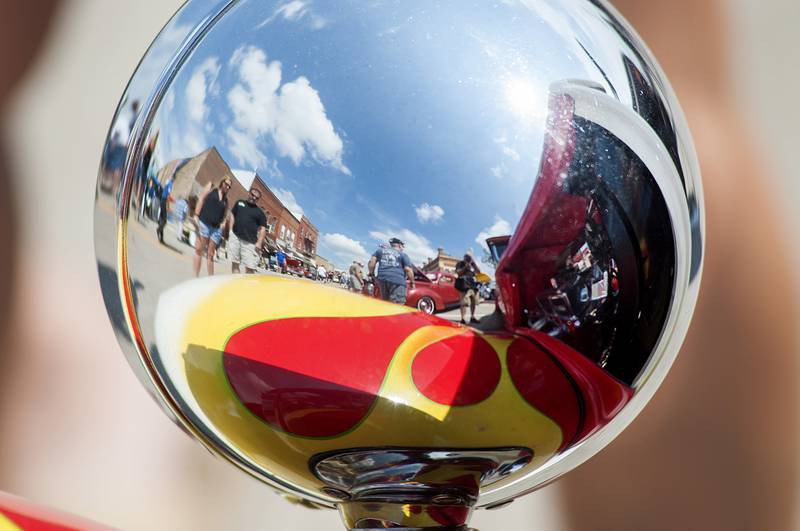 Amboy’s downtown is reflected in the headlamp of a hot rod put on display during the annual car show Sunday, Aug. 28, 2022.