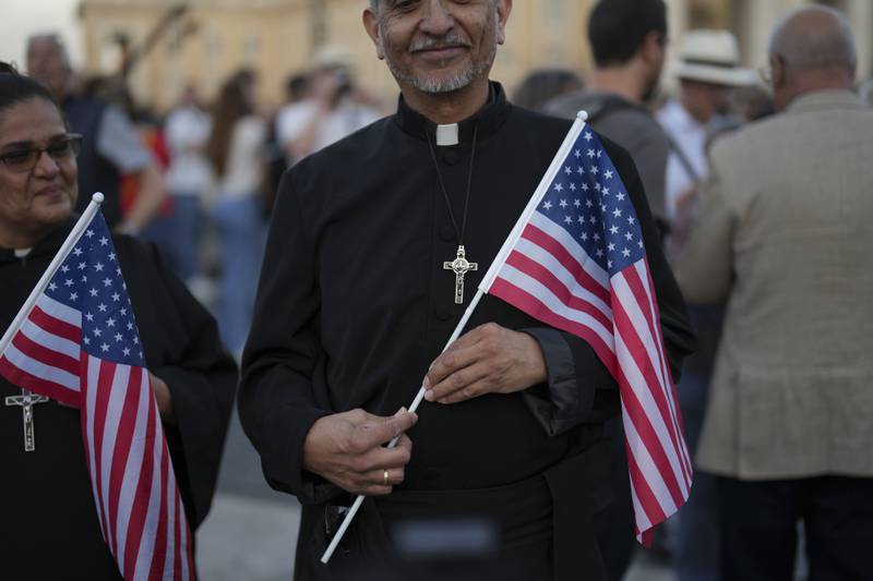 Clerics hold US flags during the speech of the newly elected Pope Leo XIV at the Vatican, Thursday, May 8, 2025. (AP Photo/Francisco Seco)
