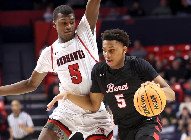 Benet's Perry Tchiegne drives by Marist's Stephen Brown Saturday, March 14, 2026, during their IHSA Class 4A state championship game in the State Farm Center at the University of Illinois in Champaign.
