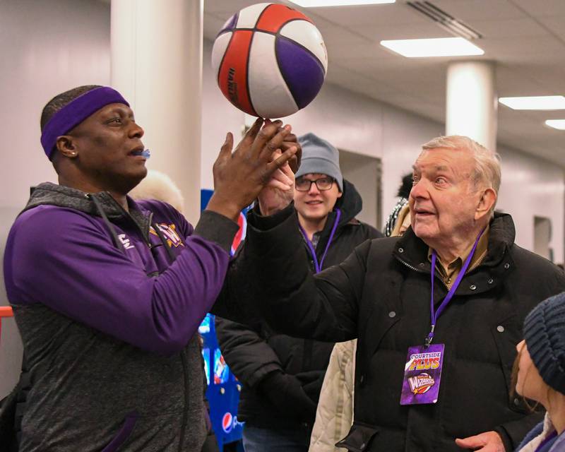 Harlem Wizard player Space Jam, left, helps spin the ball Earl Bergerseon of Winnetka on Sunday Jan. 19, 2025, before the start of the Harlem Wizard game held at Downers Grove South High School.