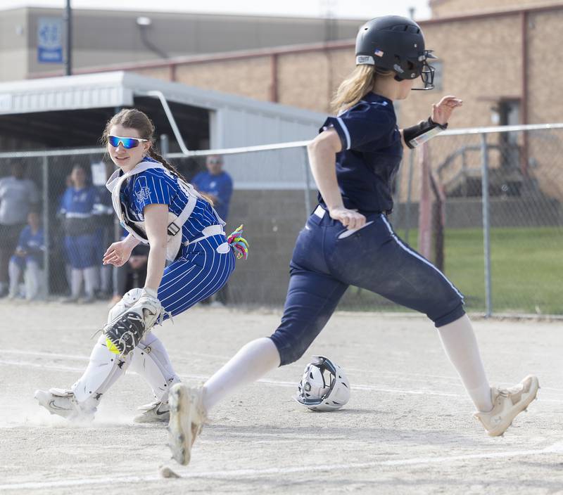 Newman’s Kaylee Benyo reaches back but was too late to tag out Bureau Valley’s Sadie Bailey who scored the first run for the Storm Wednesday, April 16, 2025.