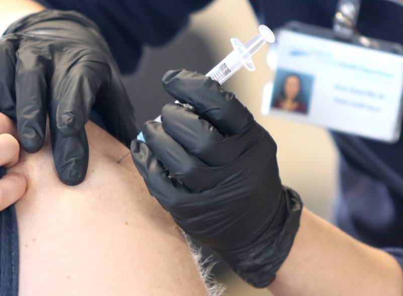 A City of DeKalb firefighter receives an injection of the Moderna COVID-19 vaccine from DeKalb County Health Department public health nurse Alex Diehl Thursday in DeKalb.