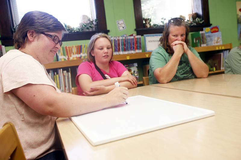 Brooke Wackerlin (center) and Amy Wackerlin (right) nervously wait their turn as Sara McAllister offers her handwriting sample.