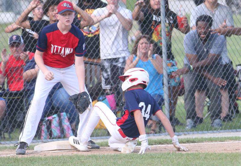 Streator All Stars Joey Studnicki slides in safely to third base as Ottawa American's Mason Collins watches the play during the District 20 championship game on Sunday, July 14, 2024 at Washington Park in Peru.