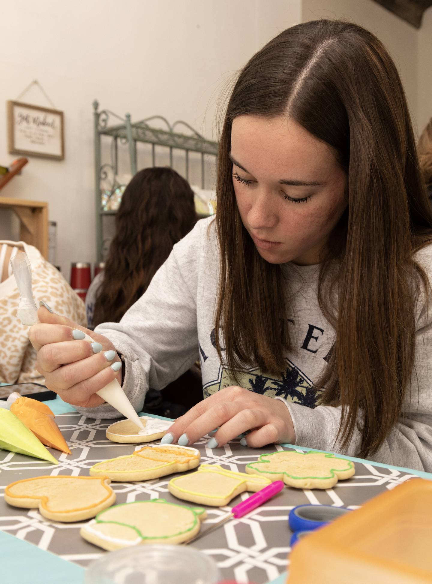 Aubry Farrell, a Marquette Academy sophomore, floods the base of her rainbow cookie with white royal icing Thursday, March 16, 2023.