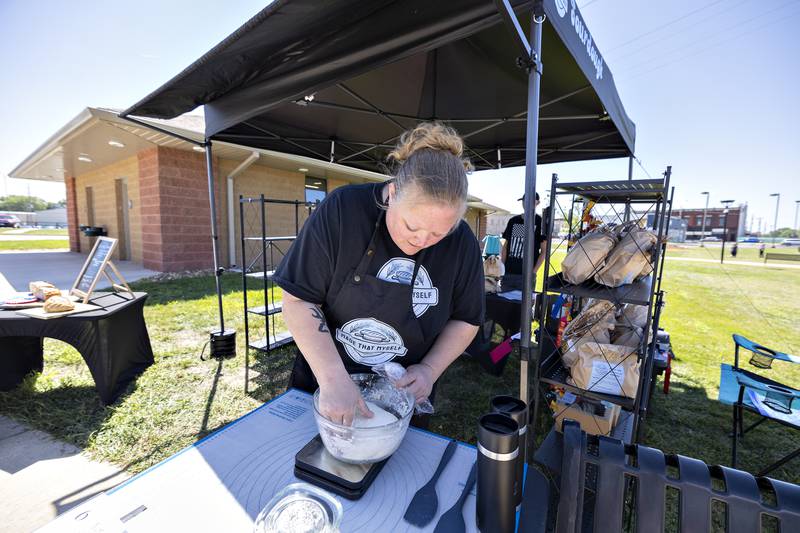 Angel Richmond, owner/baker of Made That Myself, kneads a sourdough loaf Saturday, August 23, 2025, at the Art in the Park sculpture walk in Rock Falls. Richmond was a bit unsure how the dough would react to the warm weather.