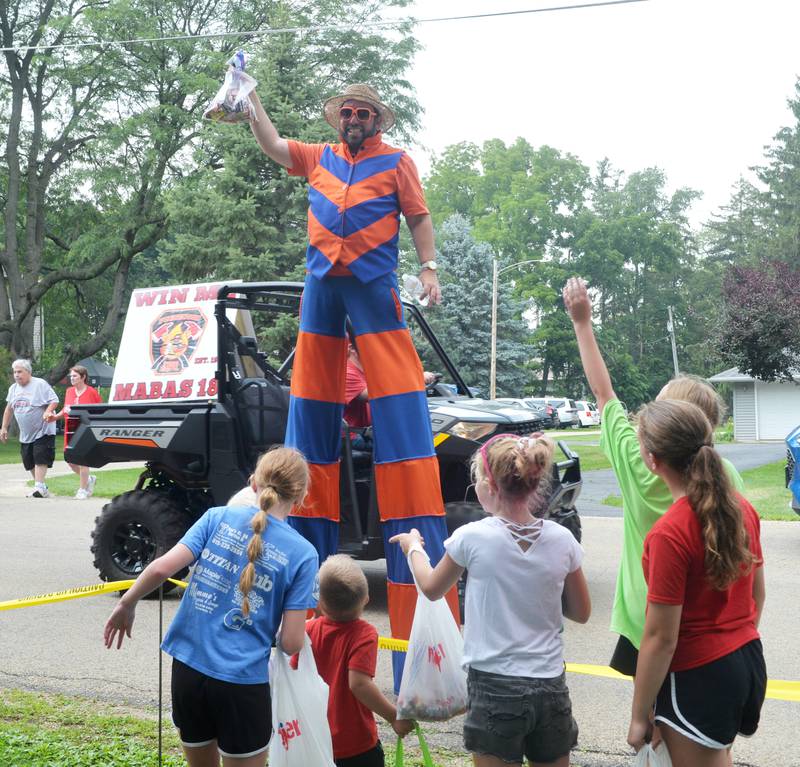 Stiltwalker Jason Kollum tries to auction off a bag of candy he captured from one of the spectators at the German Valley Days parade on Saturday, July 15, 2023. Kollum returned the bag for a high five.