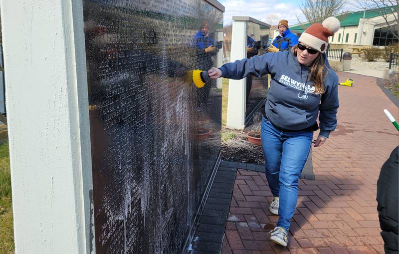 A member of the RiverGlen Christian Church wipes down the Middle East Conflicts Memorial Wall on Wednesday in Marseilles.