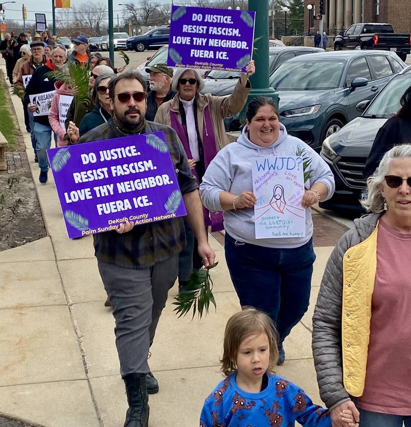 Participants hold signs during a procession at a Palm Sunday Faith Action event on Sunday, March 29, 2026, in front of the DeKalb County Courthouse in Sycamore. Area Christian ministers organized the event to combat the rise of Christian nationalism in the U.S.